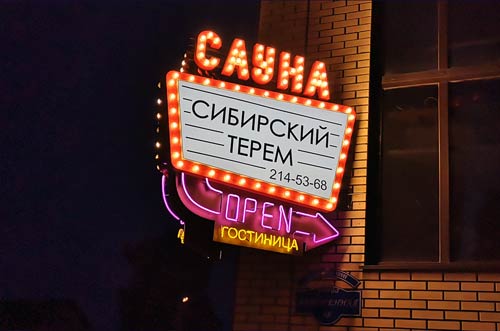 Наружняя рекламная вывеска с неоном и ретро-буквами гостиница и сауна.